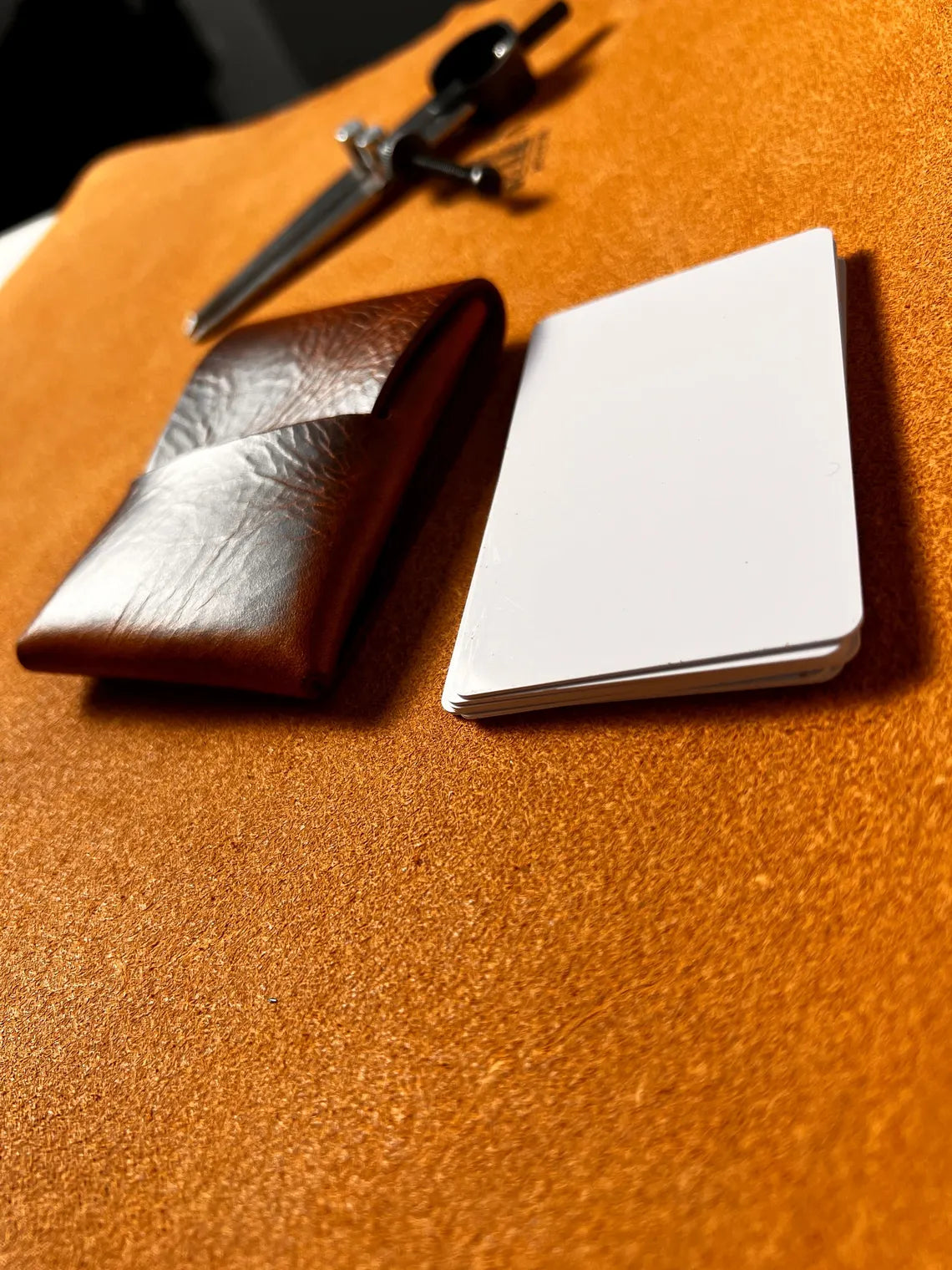 Brown leather wallet and silver cardholder on a brown surface